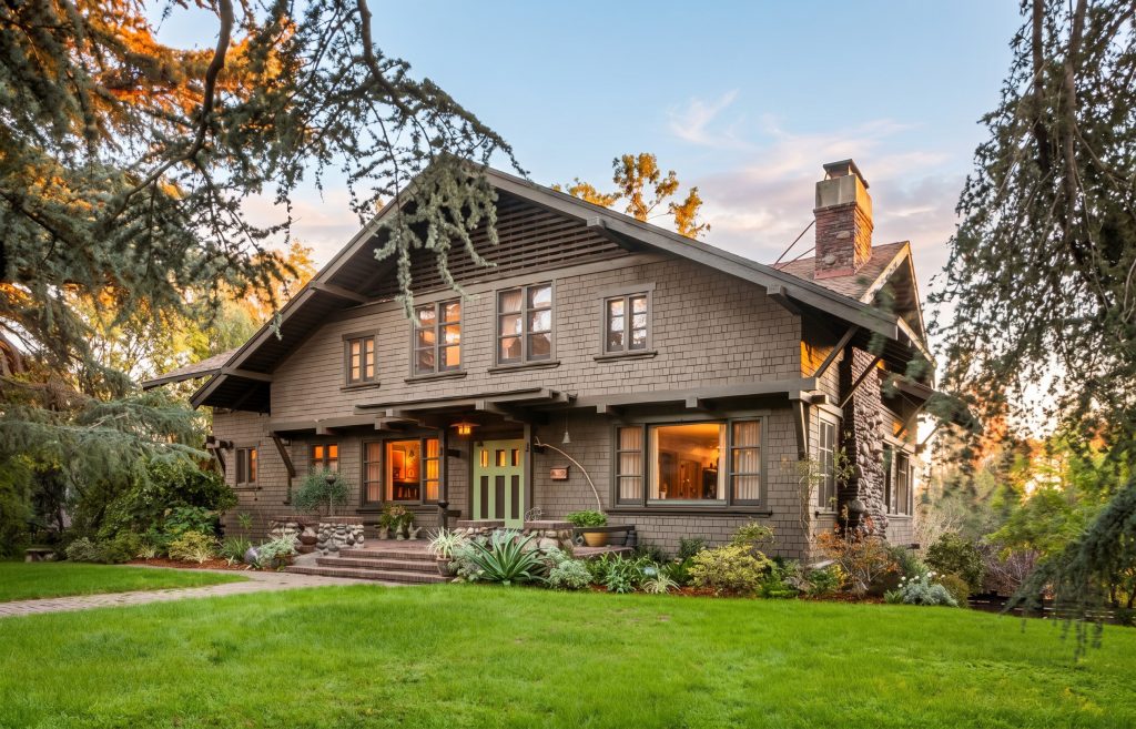 Twilight view of the Lucretia Garfield House with two-story Craftsman wood shingles and lush lawn