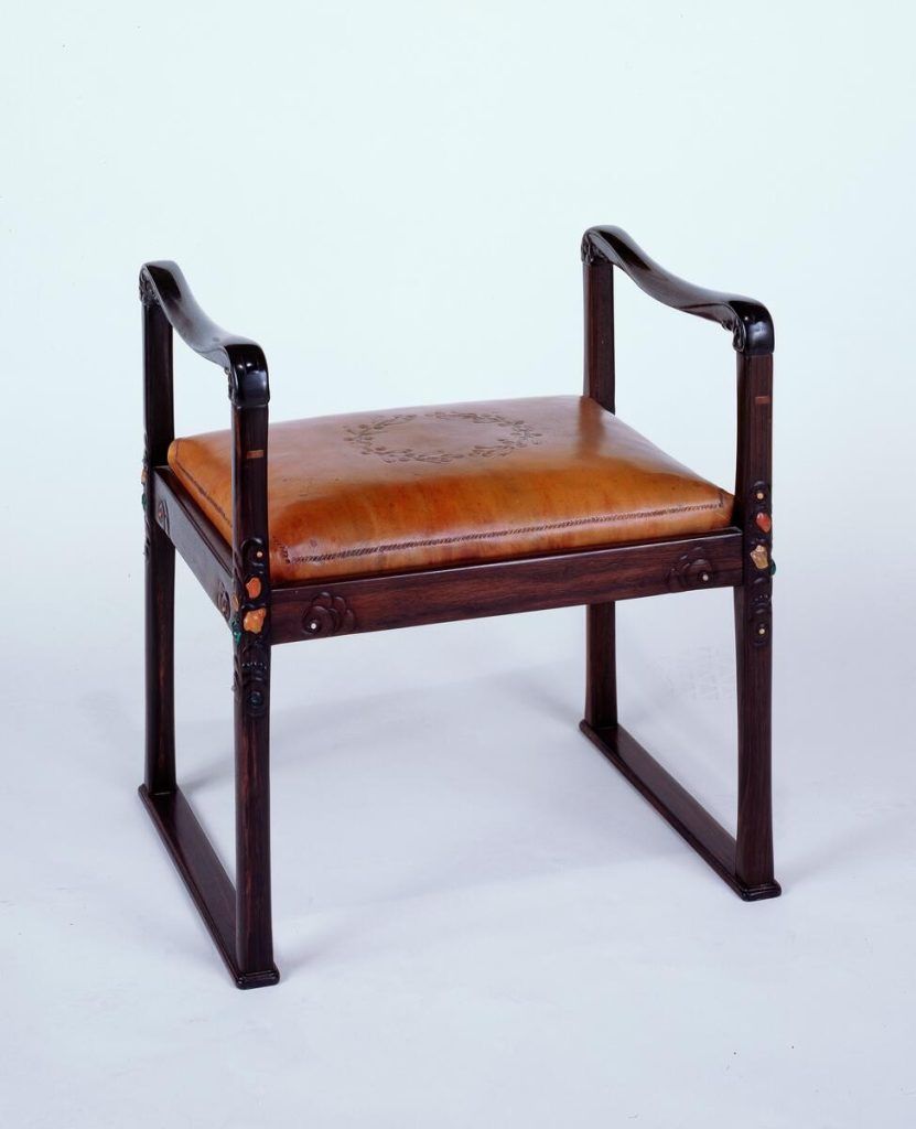 Mary J. Moore stool by Charles Greene with ebonized wood frame, tooled leather seat, and inlaid semi-precious stones in carved ebony plugs
