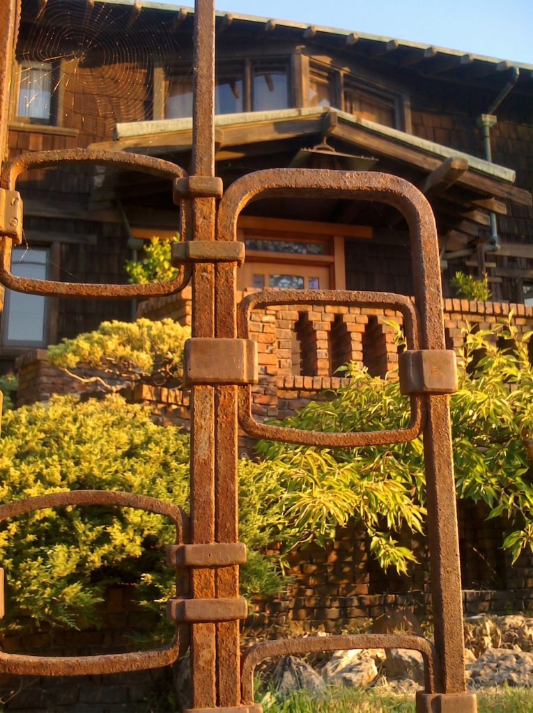 Detail of the Thorsen House wrought-iron entrance gate showing interlocking ironwork, Viking ship panel, and clinker brick piers