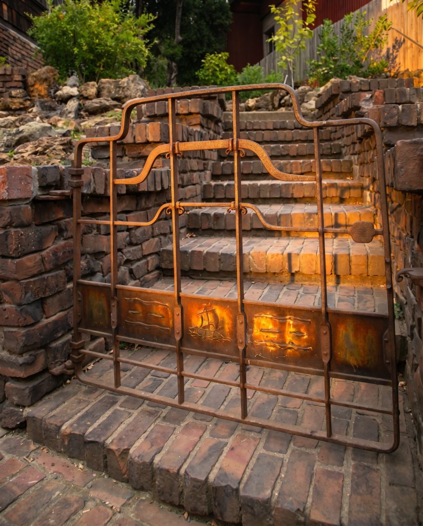 Wrought-iron entrance gate to the Thorsen House framed by clinker-brick piers with hanging lantern