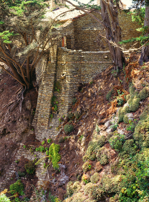 Detail of the west terrace foundation at the D.L. James House showing the boundary where dressed granite masonry meets the natural bedrock of the cliffside, the two nearly indistinguishable in the layered stone courses
