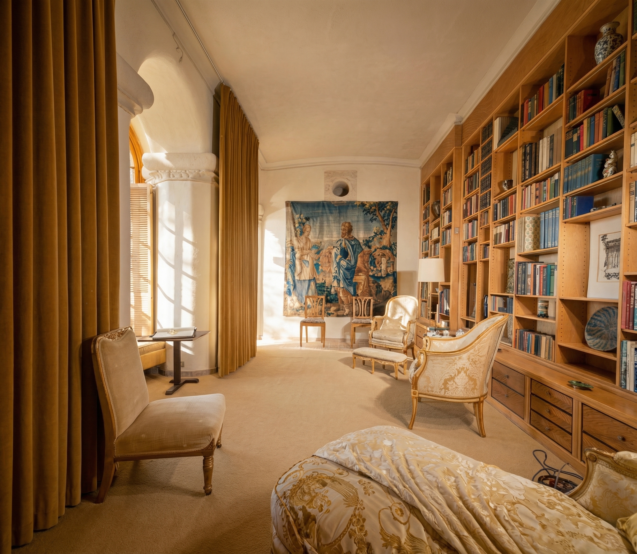 Interior of the library at Seaward showing three deep arched window portals framing views of the Pacific Ocean in sequence, with stone walls, wood floor, and built-in bookcases, the proportions calibrated to a seated reader