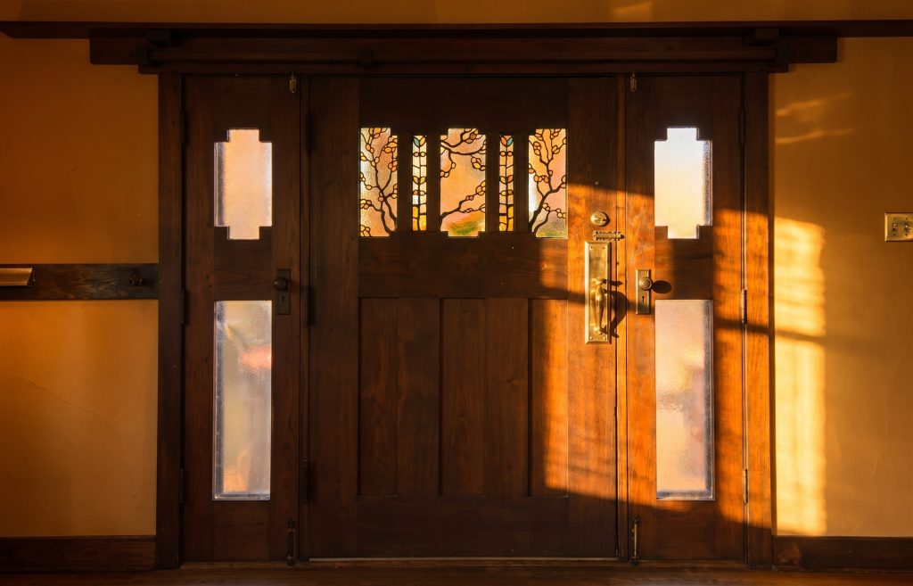 Interior side of the front door of the Louise T. Halsted House, showing detailed woodwork and a panel of leaded art glass set into the upper part of the door