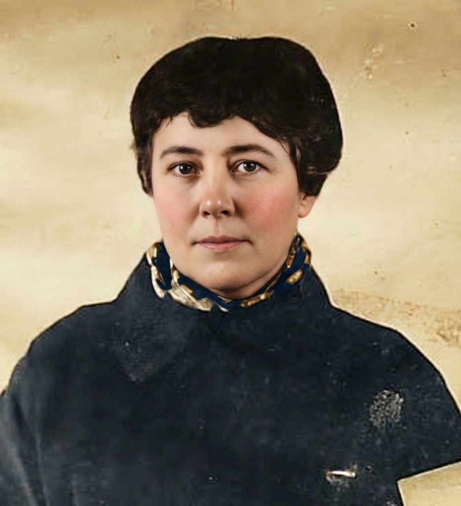 Colorized studio portrait of Laurabelle A. Robinson with dark upswept hair wearing a dark navy high-necked garment with a patterned gold-and-blue collar.